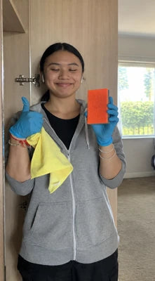 Customer wearing cleaning gloves and holding the orange pad and a yellow cloth