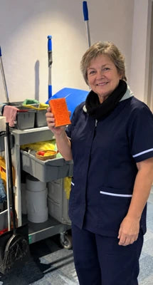 Customer holding the orange cleaning pad beside a cleaning trolley